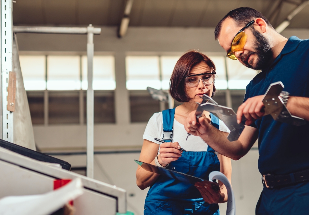 a man and woman service technicians looking at mechanical parts of a machine