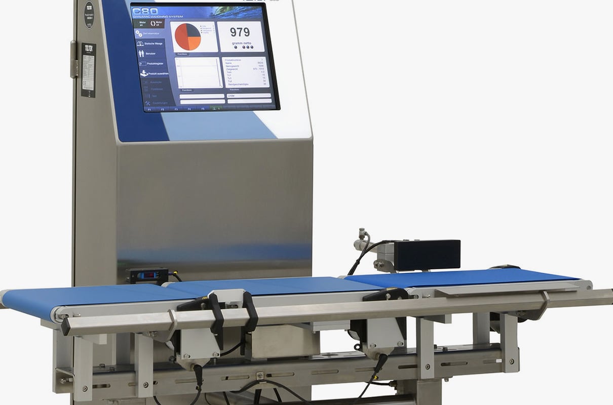 A three-quarter view of a stainless steel checkweigher system that includes a large digital display screen above a small blue conveyor belt.